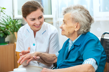 caregiver putting some cream on the hand of senior woman